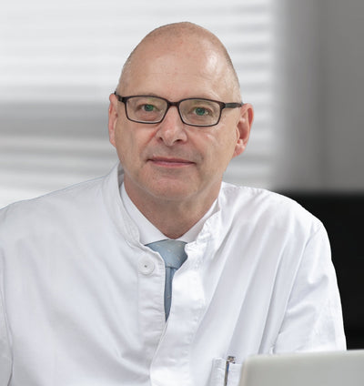 Un homme portant des lunettes et une blouse blanche