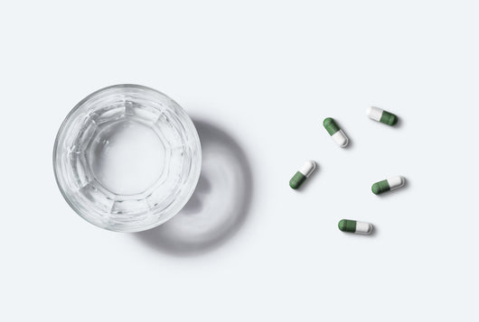 Des gélules de Kijimea disposées à droite d’une verre d’eau