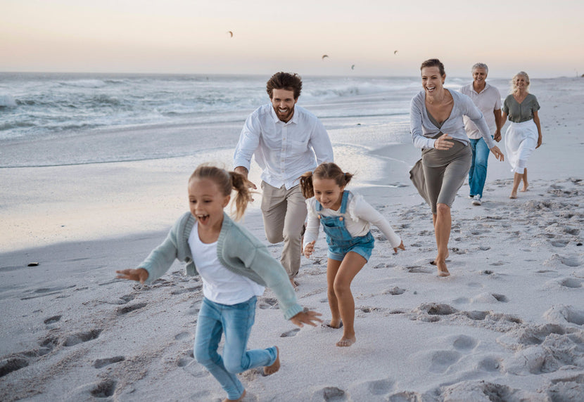 Une famille heureuse courant ensemble le long d’une plage